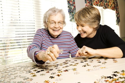 24 Stunden Pflegekraft spielt mit Seniorin puzzle